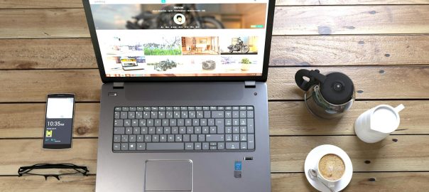 silver laptop next to coffe cup smartphone and glasses