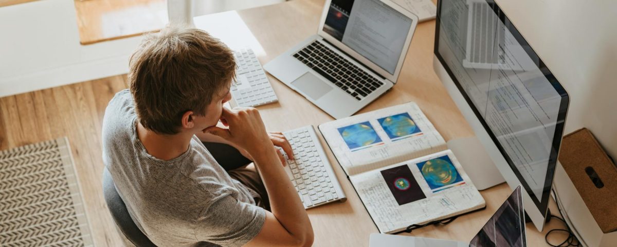 high angle shot of a boy sitting on grey chair while using his laptop computers