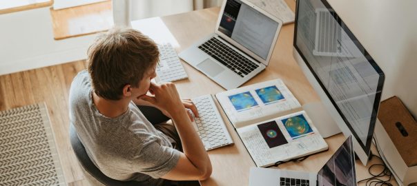 high angle shot of a boy sitting on grey chair while using his laptop computers